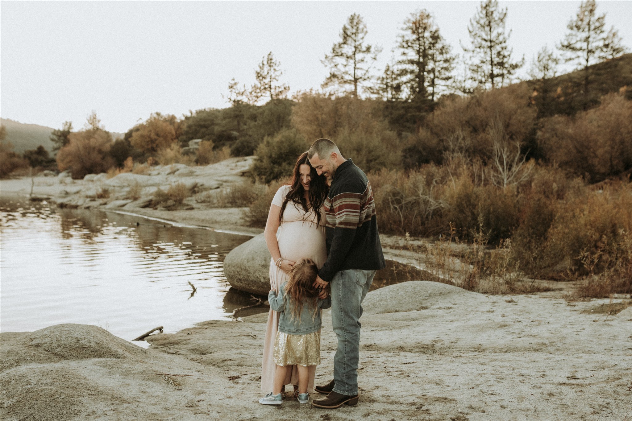 small family standing by a lake, pregnant mama, dad and child